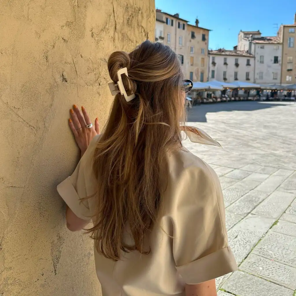 Matt kremhvit hårklemme i størrelsen large, halvt oppsatt i langt hår – by i bakgrunnen.